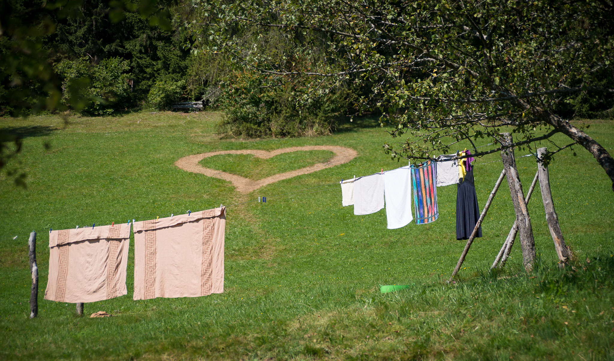 Hinter den Wäscheleinen der Pension befindet sich ein großes Herz mitten in der Wiese.